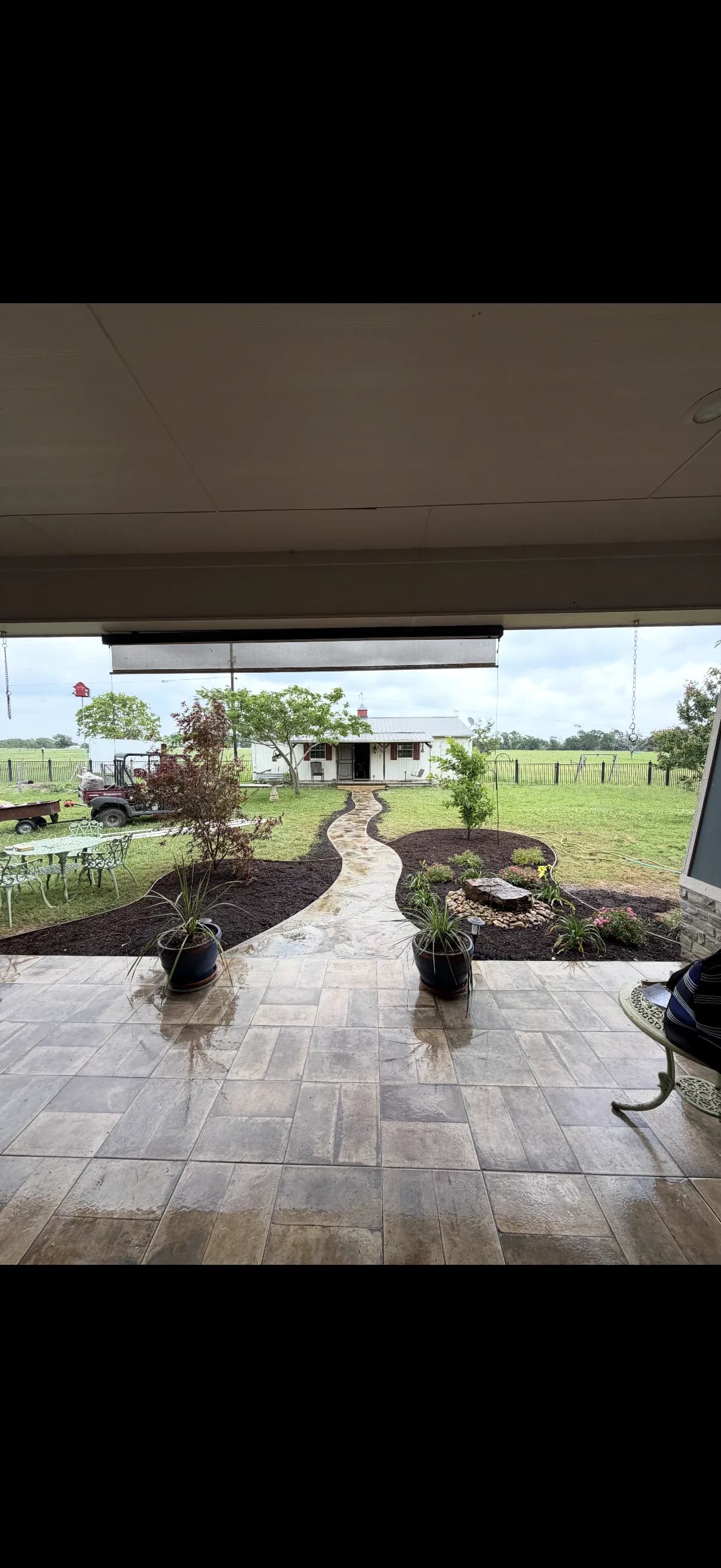 Finished flagstone walkway winding through a fresh lawn with mulched beds, a water feature, and a stone patio